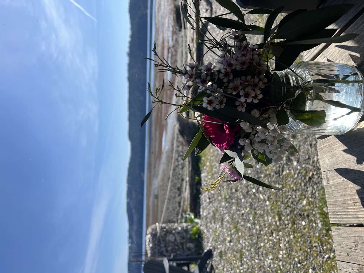 View from inside an A-frame picnic shelter at Hama Hama, flowers on the table, Hood Canal in the background